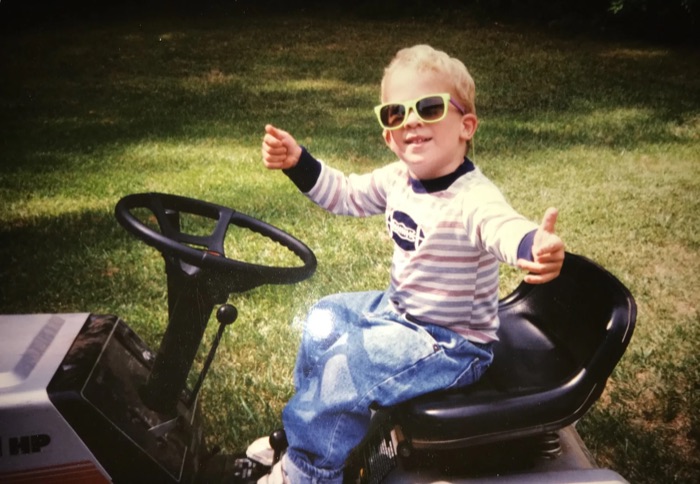 Jesse Henry as a child, driving a lawn tractor
